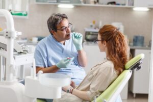 Dentist explaining his patient's situation while she sits in chair